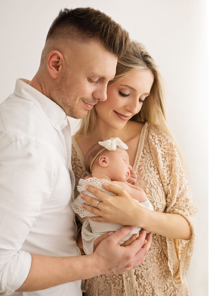 Parents with a sleeping newborn in a bright studio in Gocław